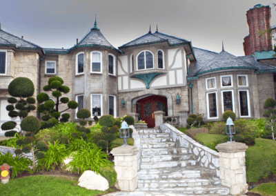Elegant stone mansion with manicured garden and twin turrets.