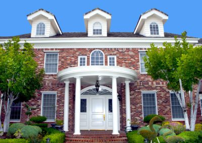 Traditional two-story brick house with white trim and an arched entrance.