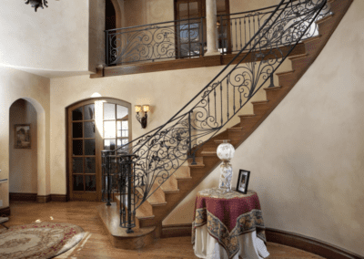 Elegant interior with curved wooden staircase and ornate iron balustrade.