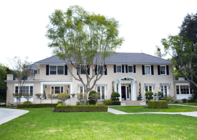 A two-story suburban home with a well-manicured lawn and a tree in the front yard.