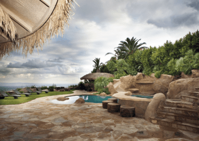 Luxurious poolside area with tropical landscaping and ocean view.